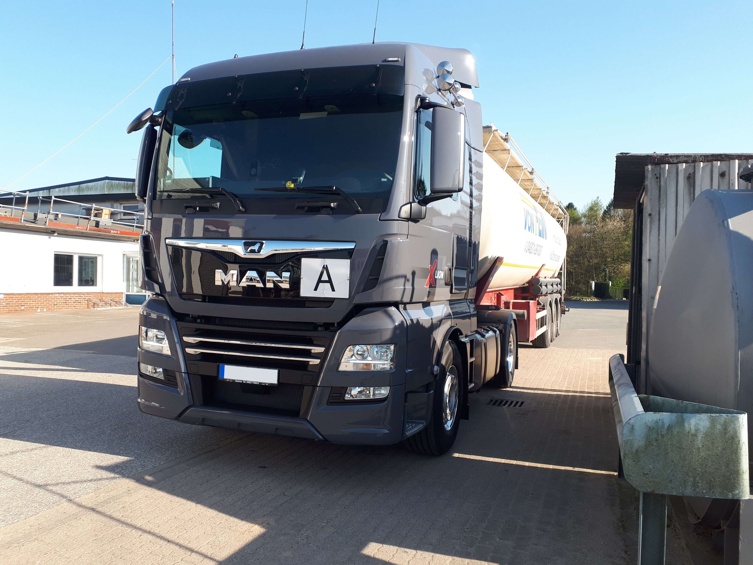 Ein graues Transportfahrzeug mit einem weißen Container hinten drauf